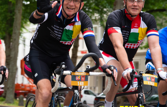 Twee wielrenners zwaaien naar de camera terwijl ze deelnemen aan de Tour d'Utrecht