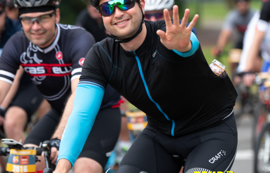 Een wielrenner zwaait naar de camera terwijl ze deelnemen aan de Tour d'Utrecht