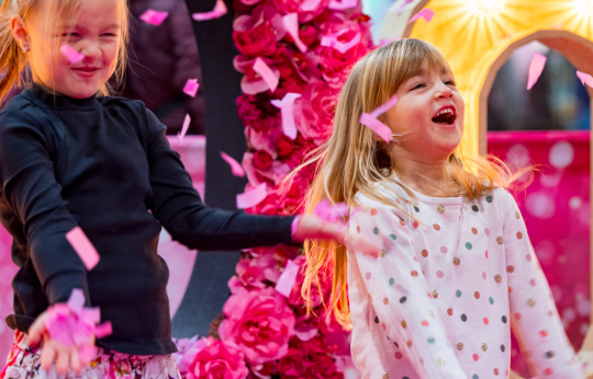 Twee kinderen springen terwijl er roze confetti valt
