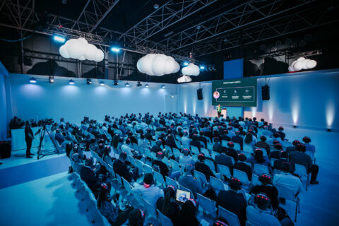 Een grote groep mensen luisteren aandachtig naar een spreker die een prestatie geeft tijdens het evenement van Microsoft.