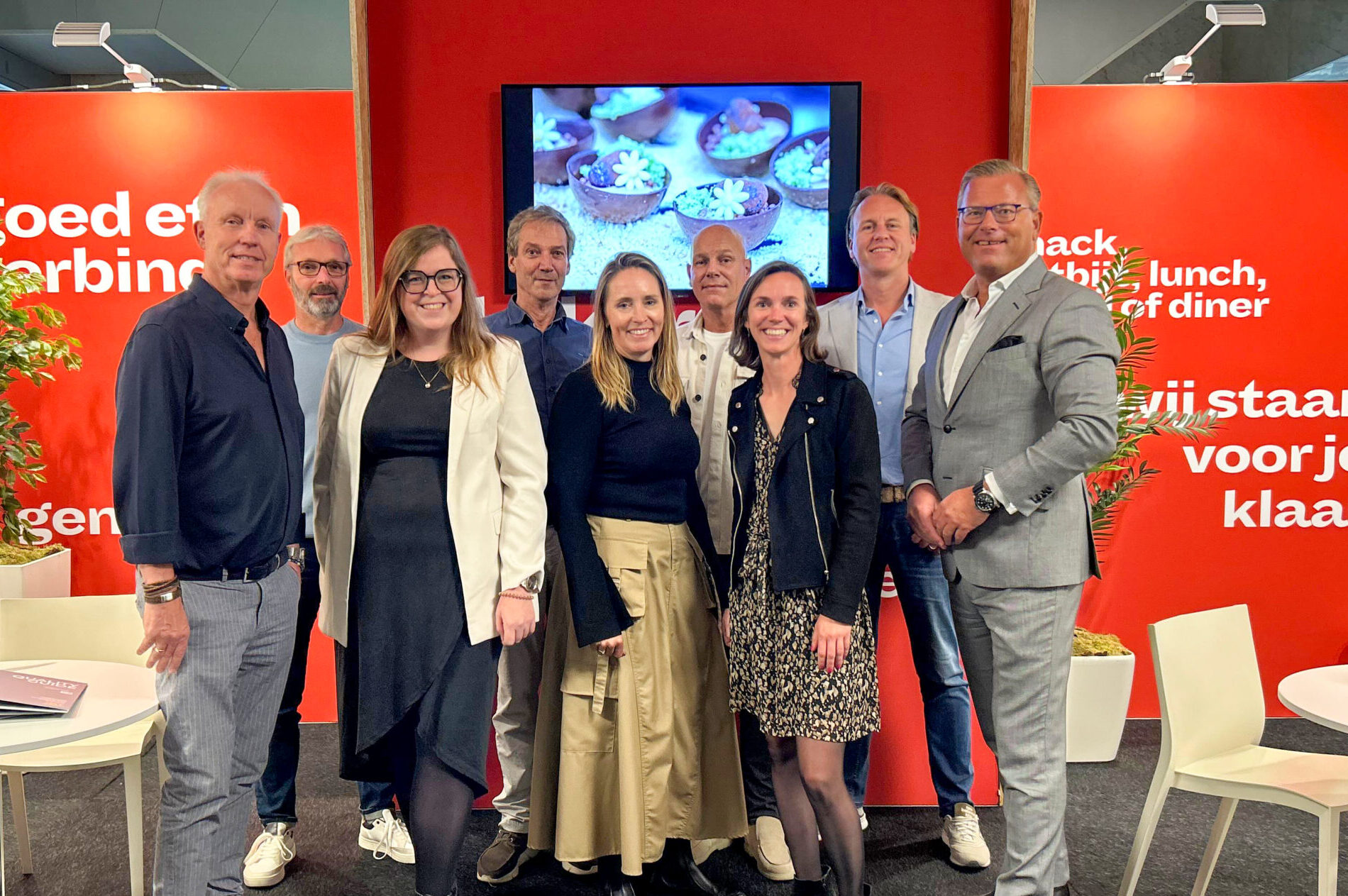 Dames en heren staan in camera te kijken bij stand
